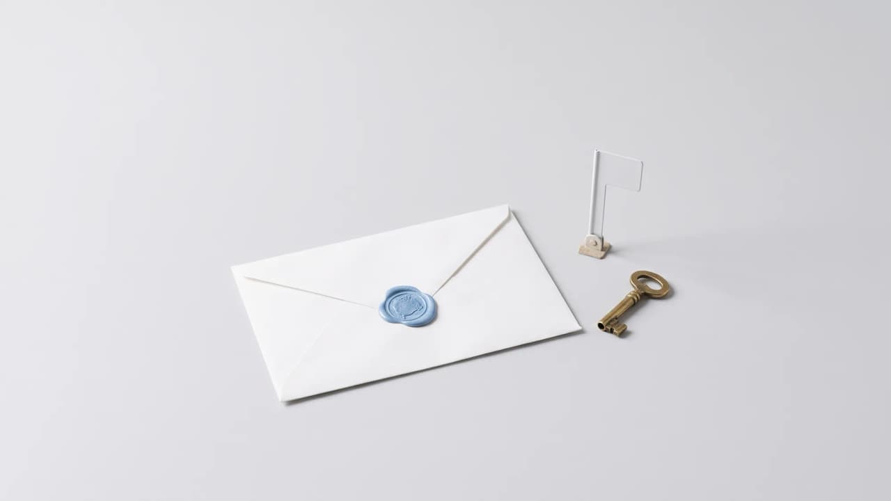 A white envelope with a blue wax seal, beside a small brass key and a tiny white flag