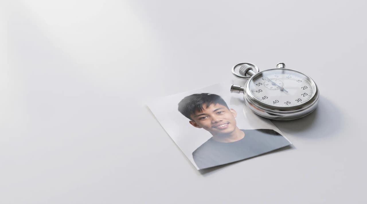 A silver stopwatch beside a printed photograph on a light grey surface